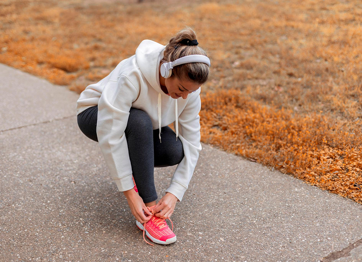 Personne en tenue de sport assise chez elle, en train de lacer ses baskets avant une séance de sport, dans une ambiance douce de rentrée en septembre.